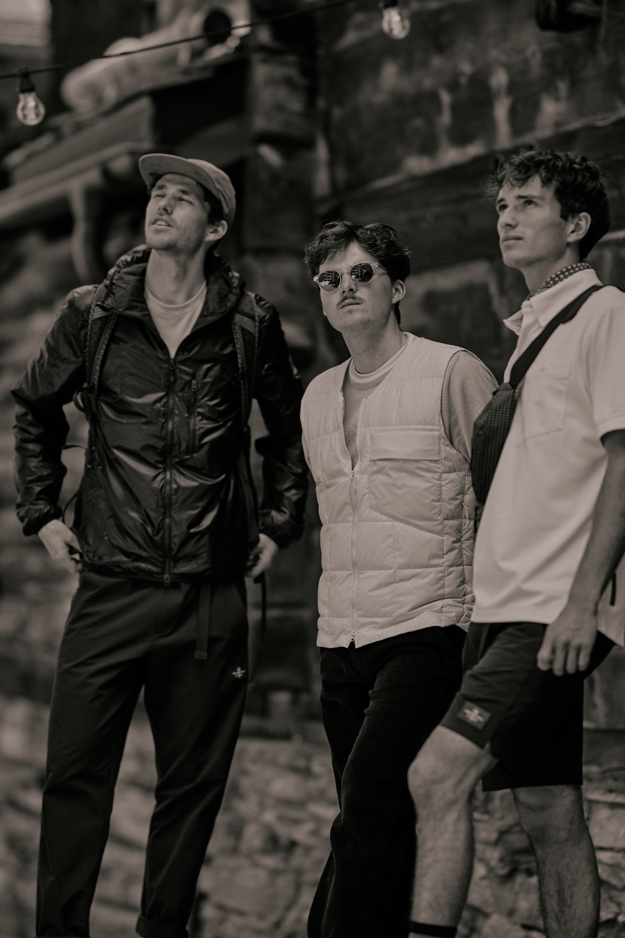 Three men in Zermatt village dressed in lightweight technical jackets, quilted vest and polo
