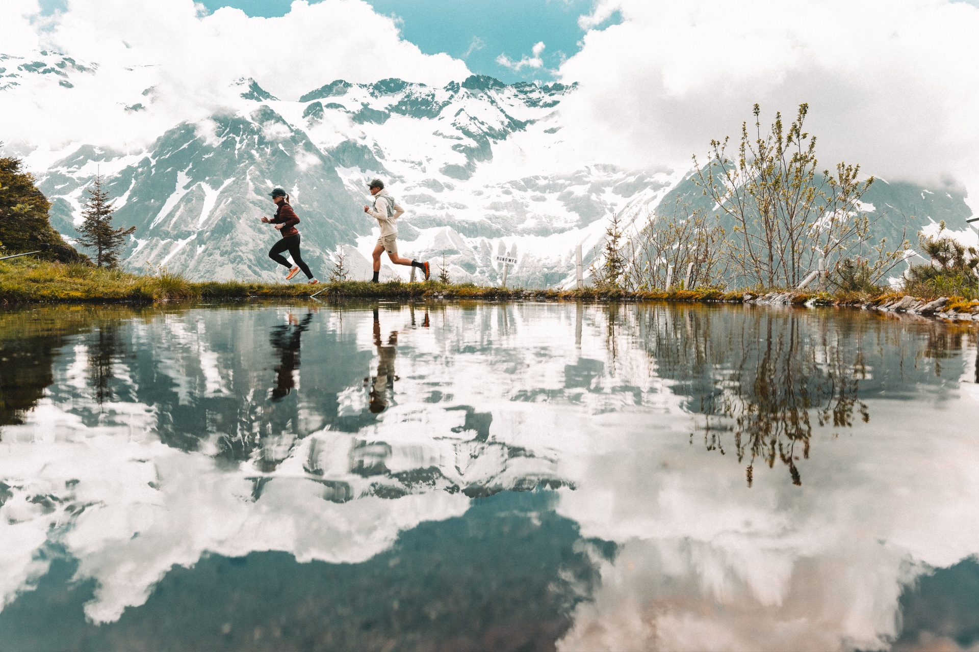 Trail runners moving through a high-alpine summer landscape.
