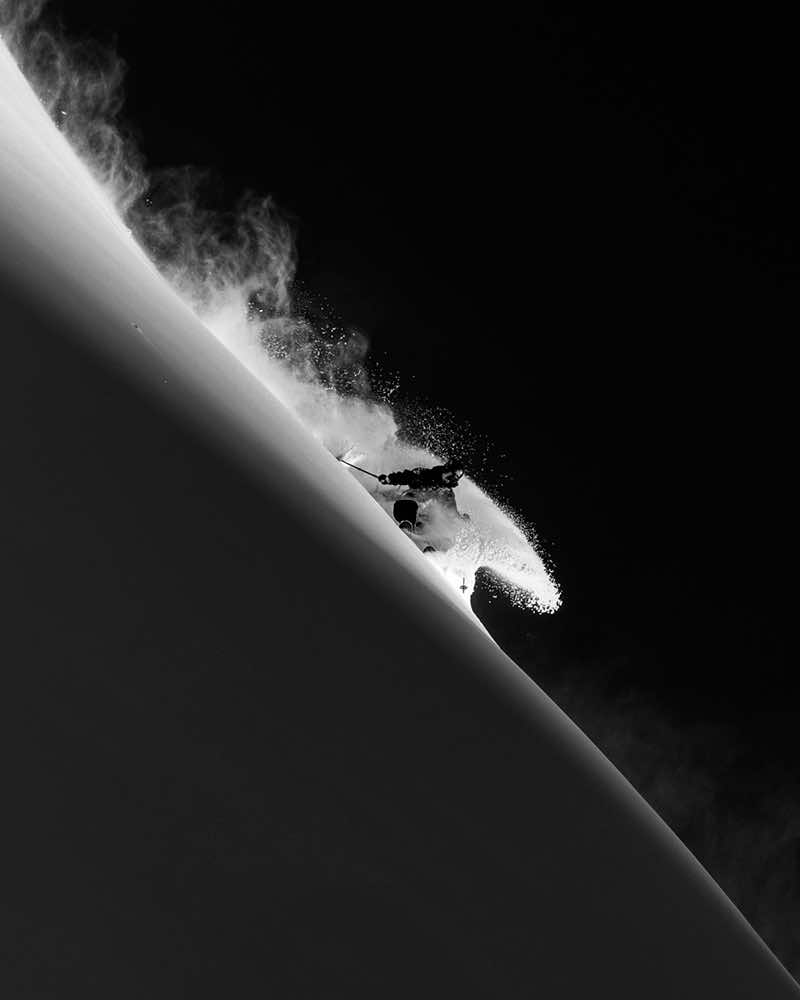 A skier descending a powder spine in low light