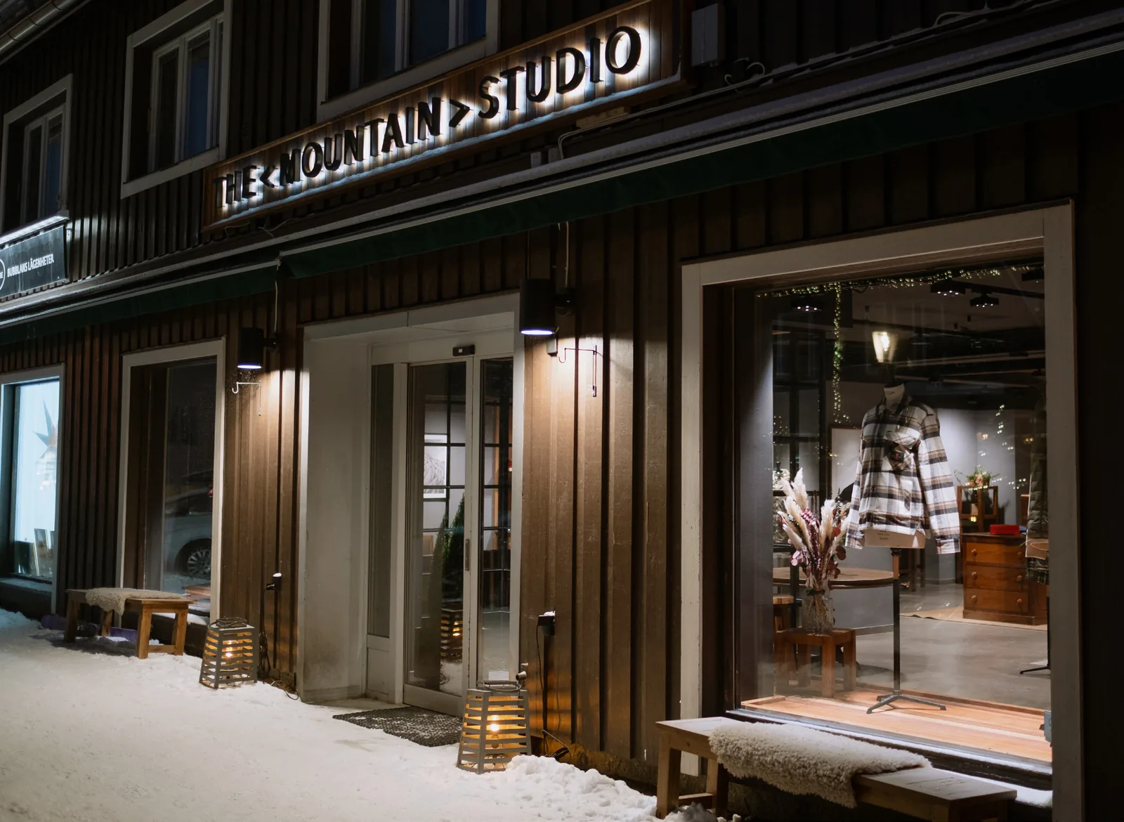 The Mountain Studio store in Åre at dusk, lit windows and snow along the timber facade