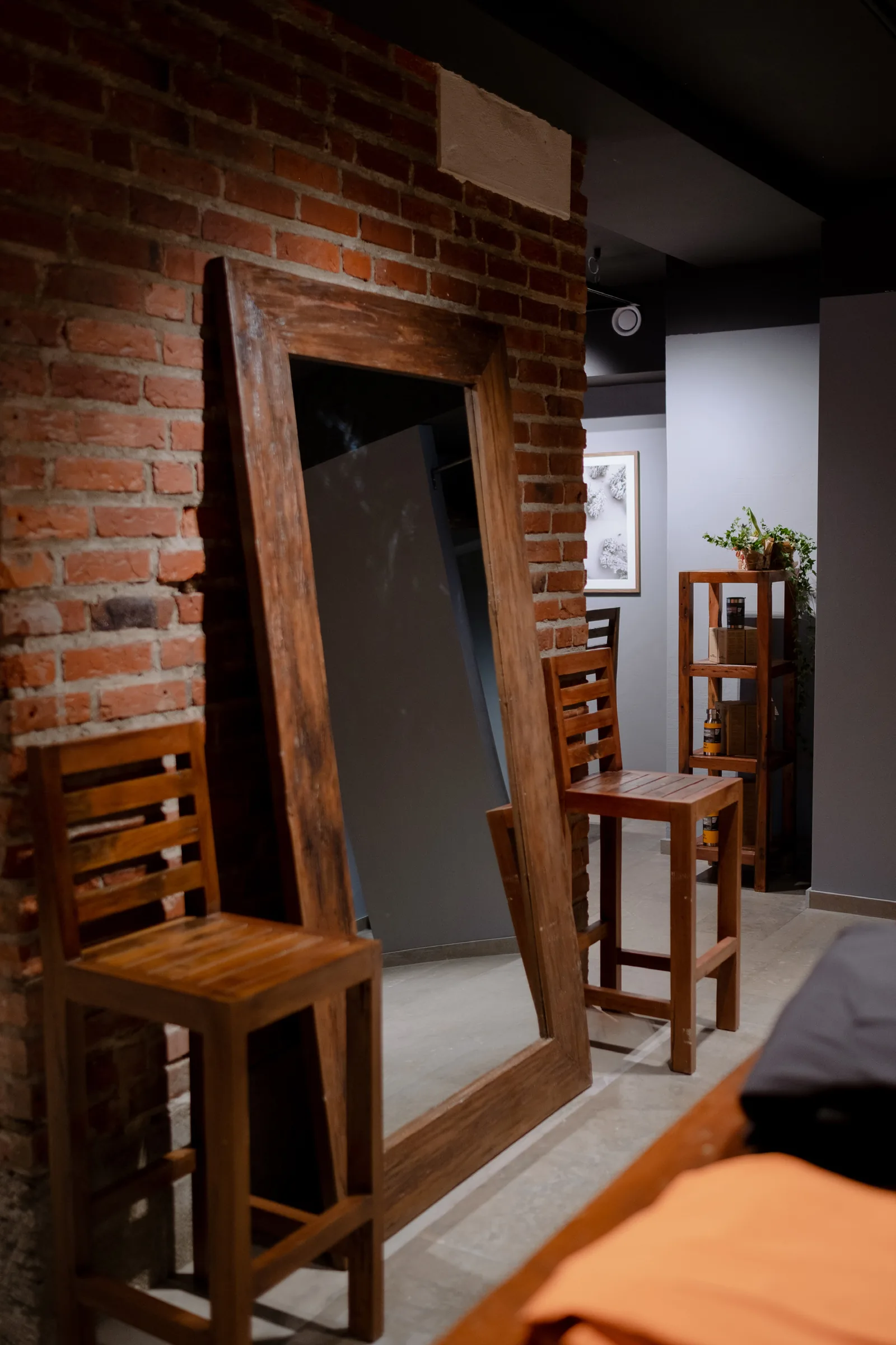Store interior with exposed brick wall, a large reclaimed-timber floor mirror and wooden stools