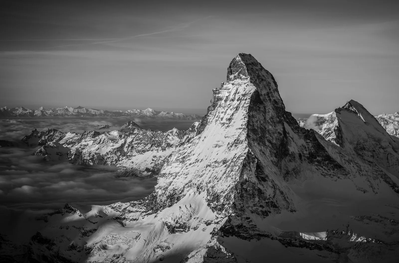 Black-and-white aerial view of the Matterhorn rising above a broad sea of cloud